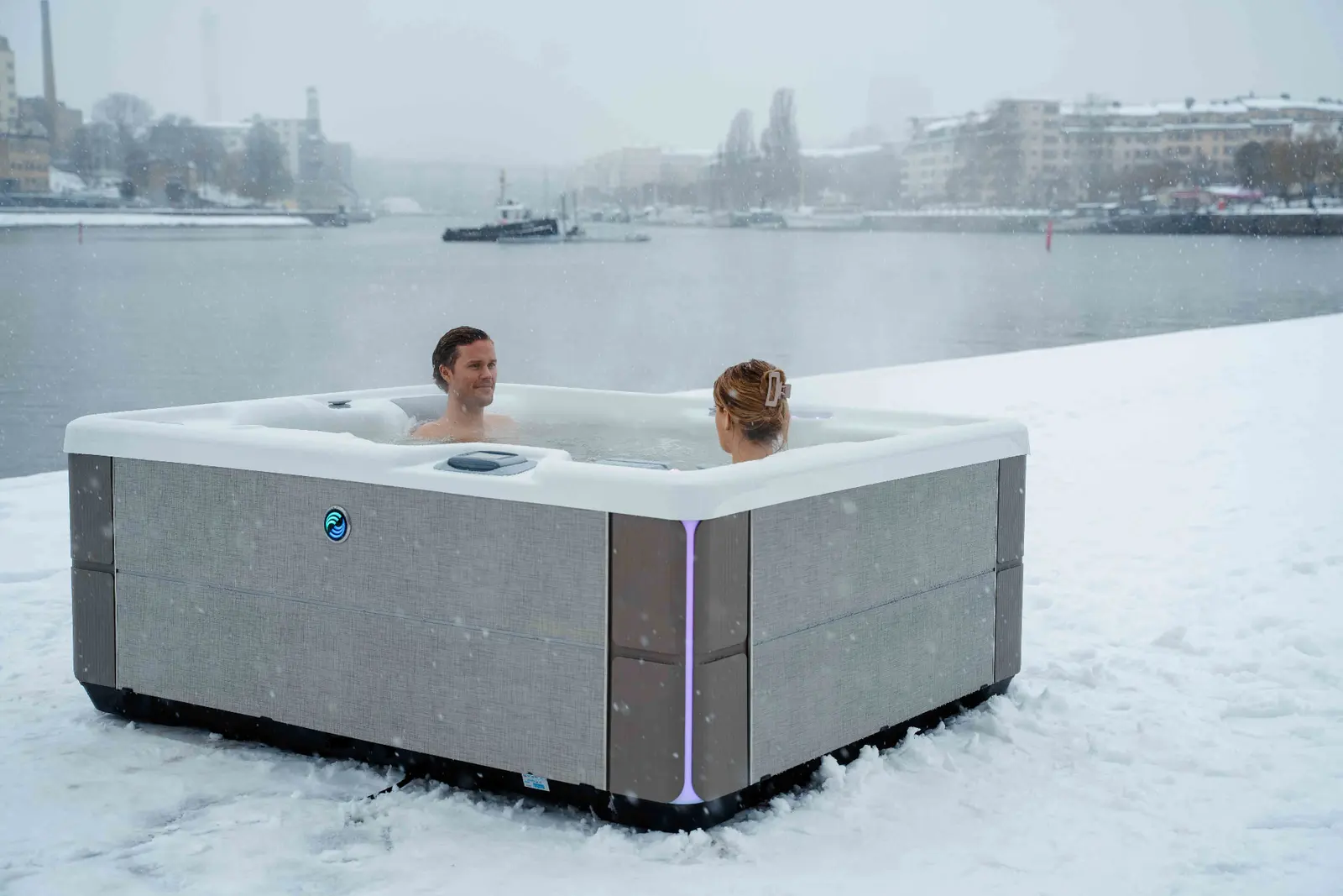 Par badar i HotSpring Highlife spabad i snö vid vattnet i Stockholm