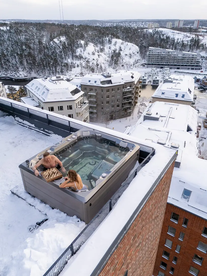 Par spelar schack i ett HotSpring Limelight spabad på ett snötäckt tak