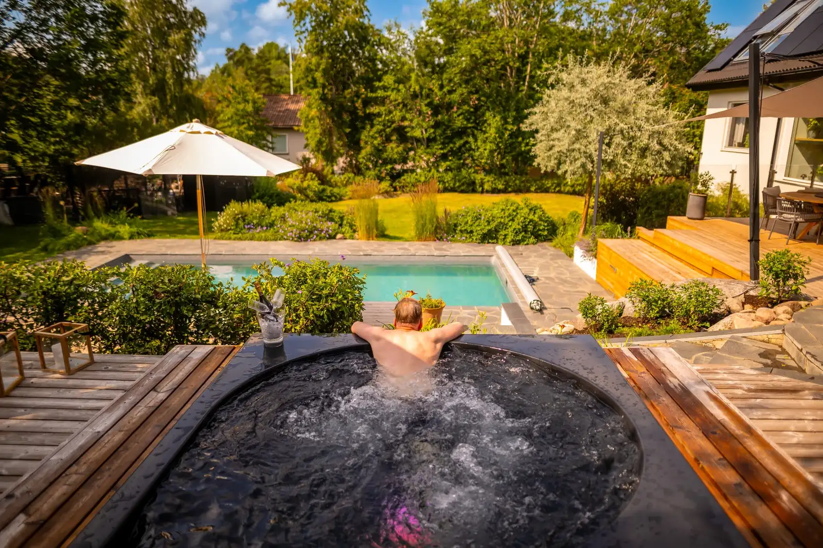 Man badar i ett Drop Design Spa med pool och trädgård i bakgrunden