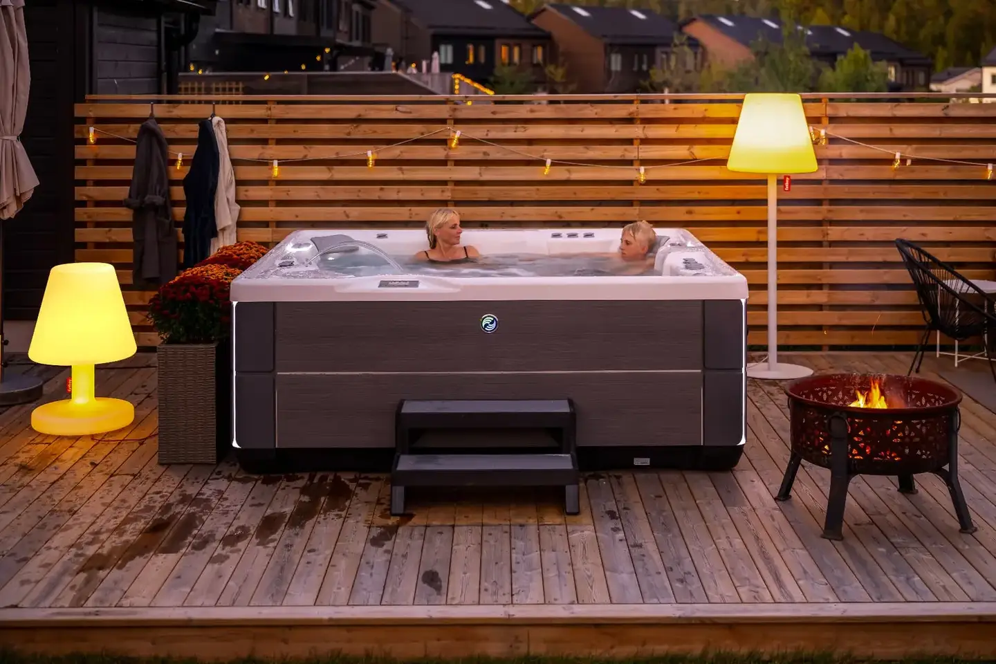 Mamma och son badar i ett HotSpring Highlife spabad en höstkväll