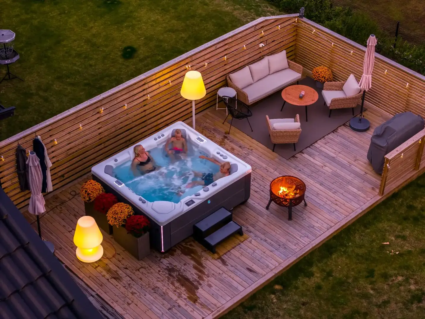Familj badar i ett HotSpring spabad på en inglasad altan en höstkväll