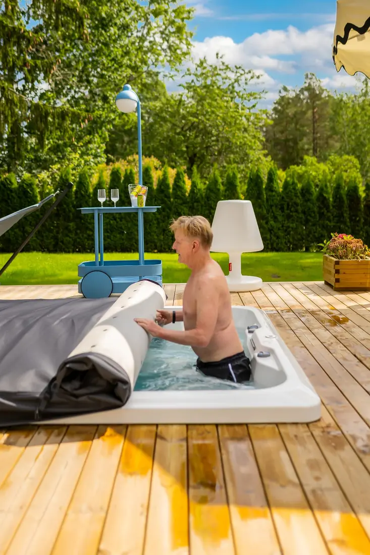 Man öppnar rullocket på ett Endless Pools swimspa inifrån vattnet