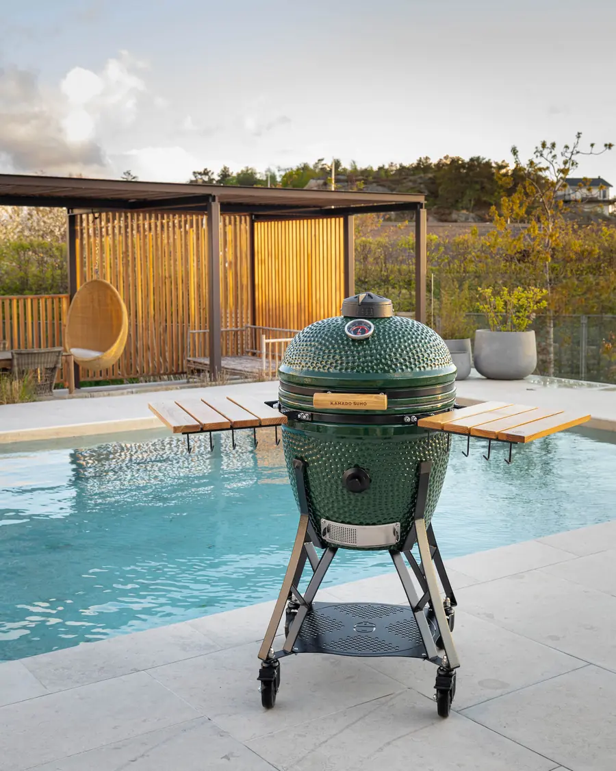 Grön KAMADO SUMO Classic Large keramikgrill vid poolkanten i kvällssol