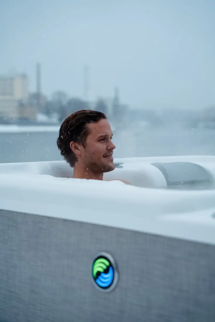 Man badar i HotSpring Highlife spabad medan snön faller