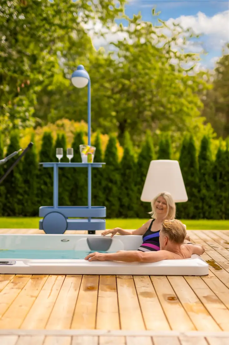 Par kopplar av i ett Endless Pools swimspa en sommardag