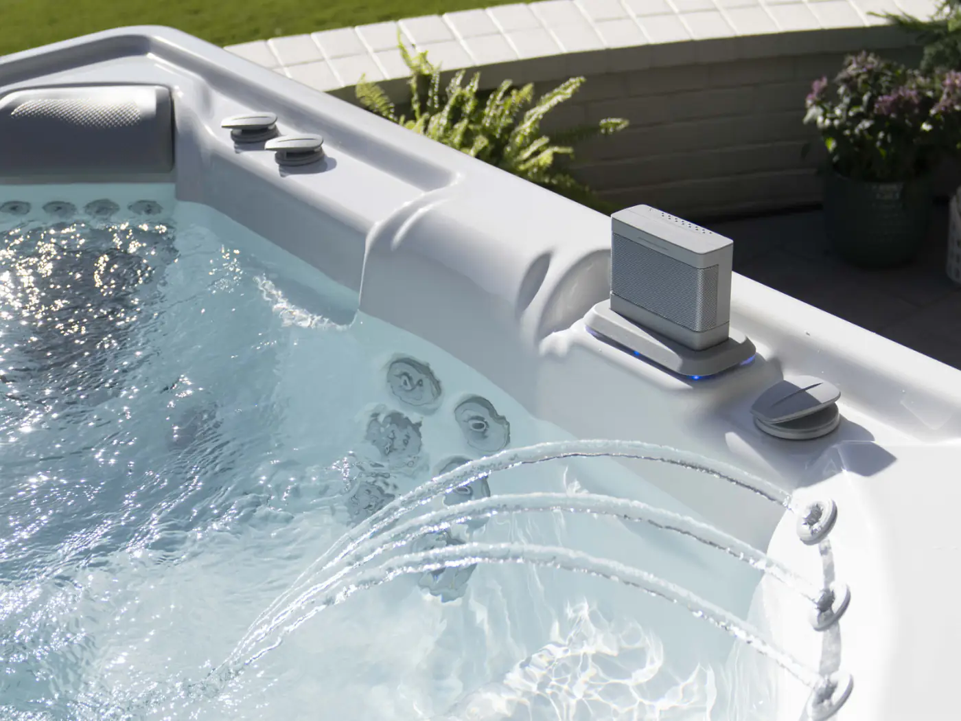 Trådlös HotSpring-högtalare i spabadets kant med belysta vattenstrålar