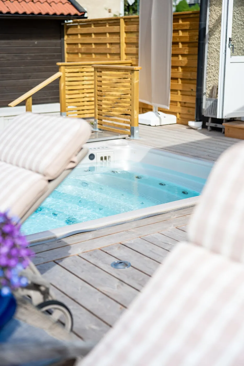 USSPA swimspa på altan en solig sommardag med dynor och parasoll intill