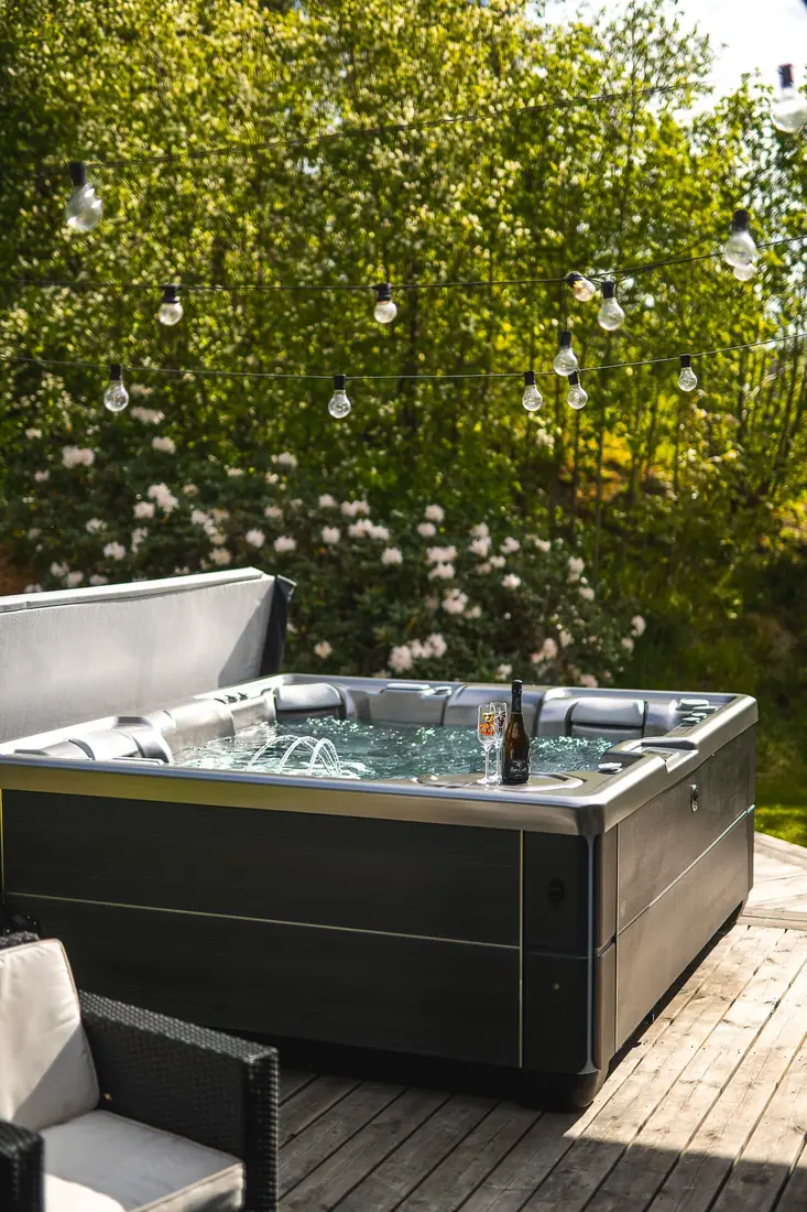 HotSpring Highlife spabad under ljusslingor med bubbel och glas en sommarkväll