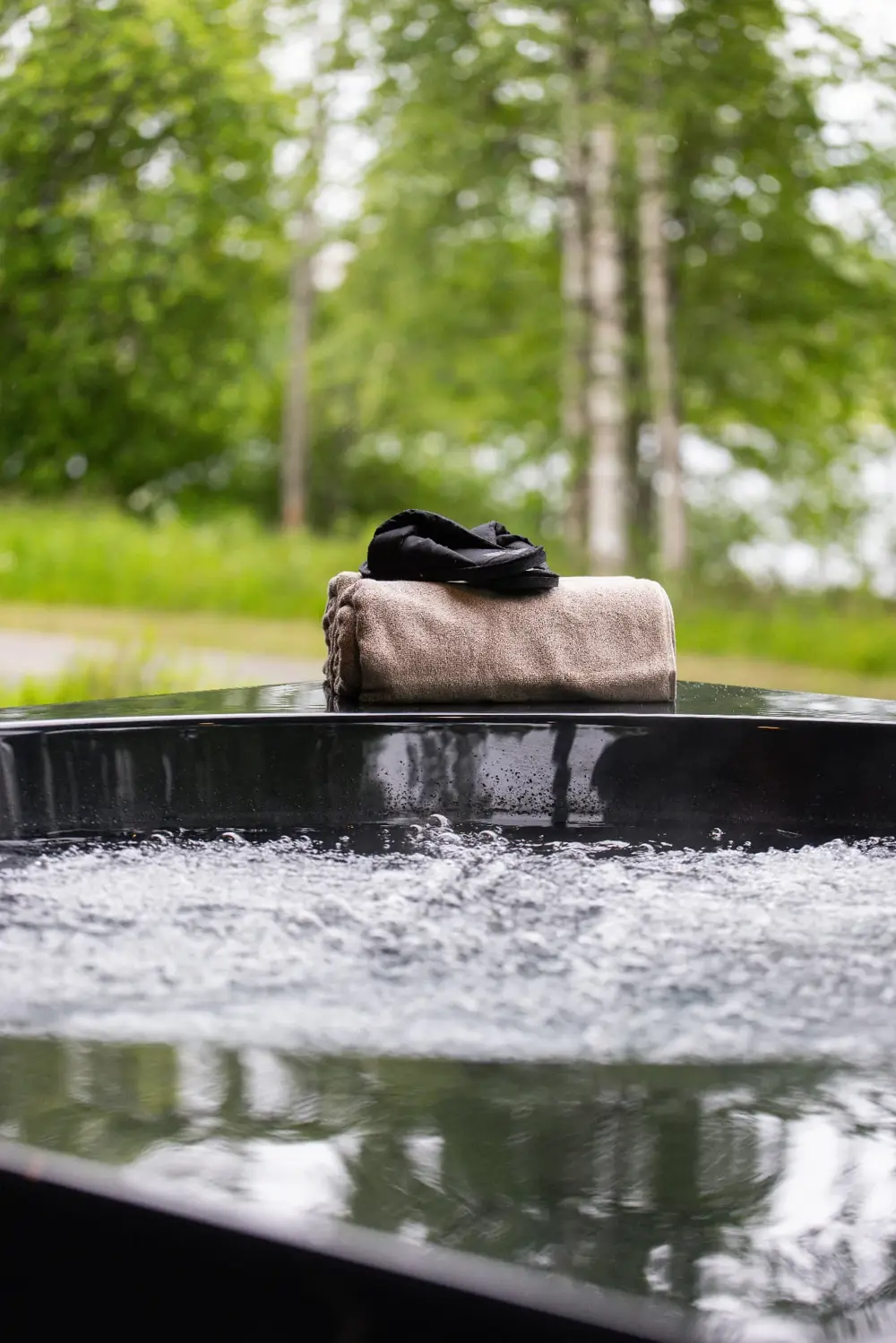 Drop Design Spa, bubblande svart bad med handduk i grönska