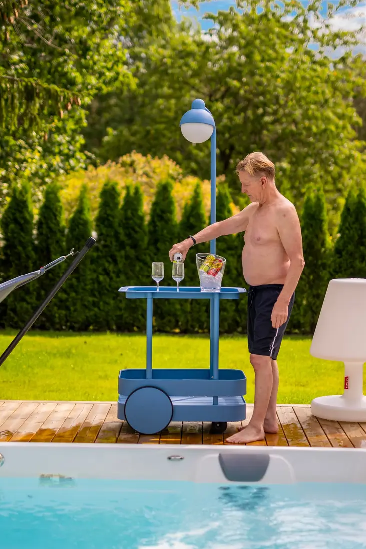 Man häller upp dryck vid ett Endless Pools swimspa en sommardag