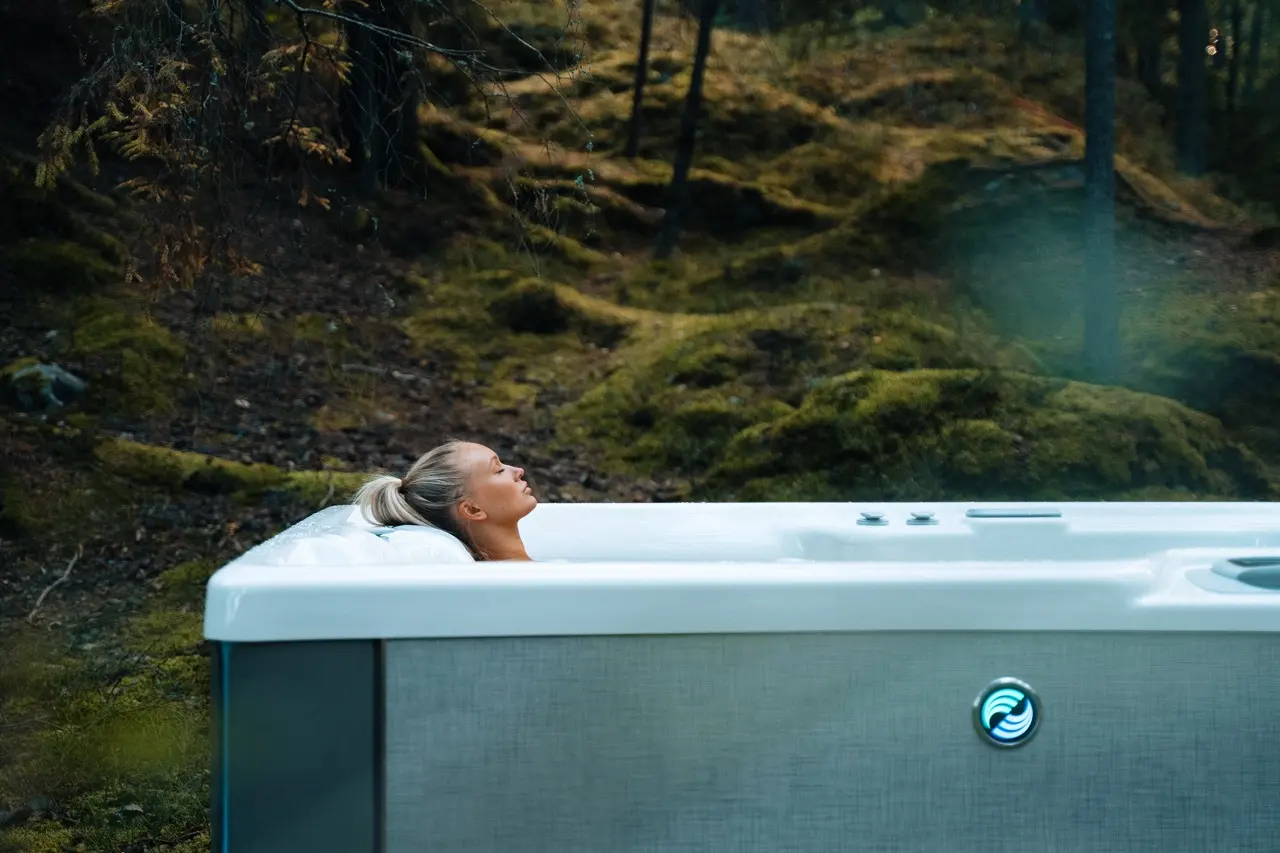 Kvinna badar i HotSpring Highlife spabad i höstskog