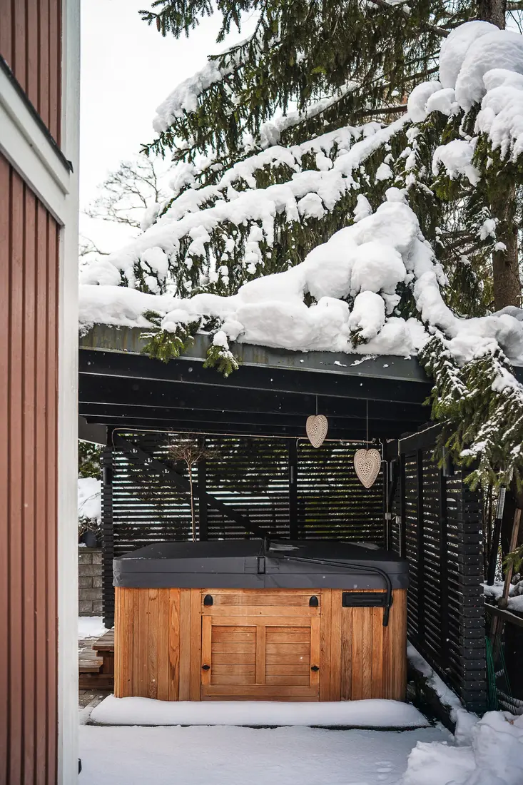 Spabad med grått SWIIM-lock under tak en snöig vinterdag