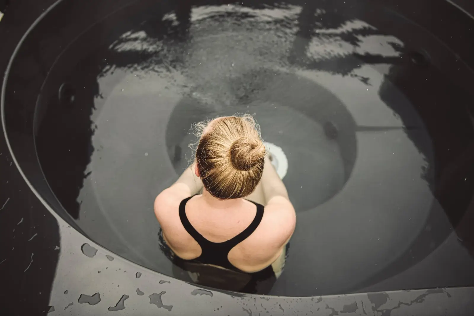 Drop Design Spa, kvinna i ett runt svart bad, sett ovanifrån, ett av baden vi levererar till Borås