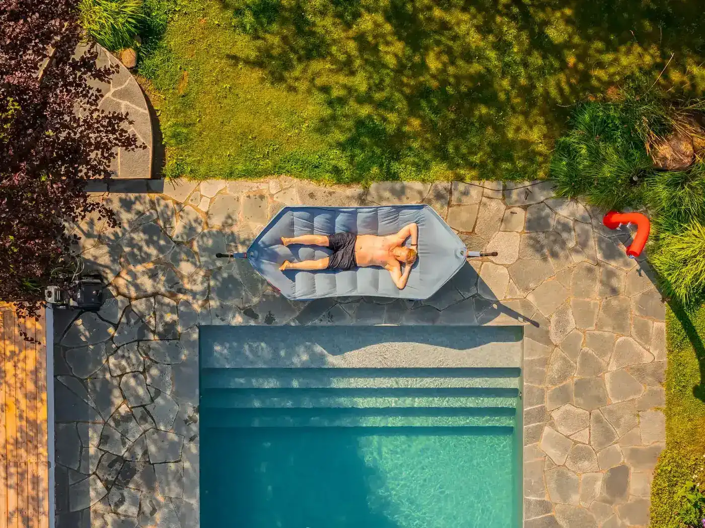 Man vilar på en Fatboy-solvila vid en pool, sett ovanifrån